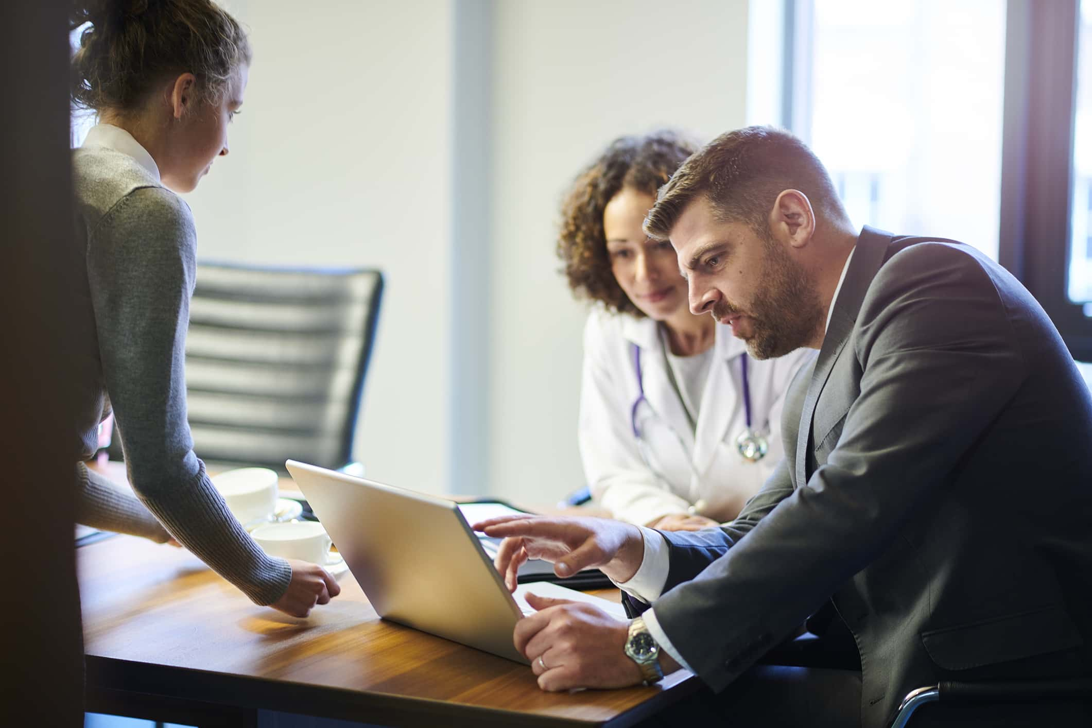 a businessman chats with a female doctor as they leave a boardroom meeting in a hospital